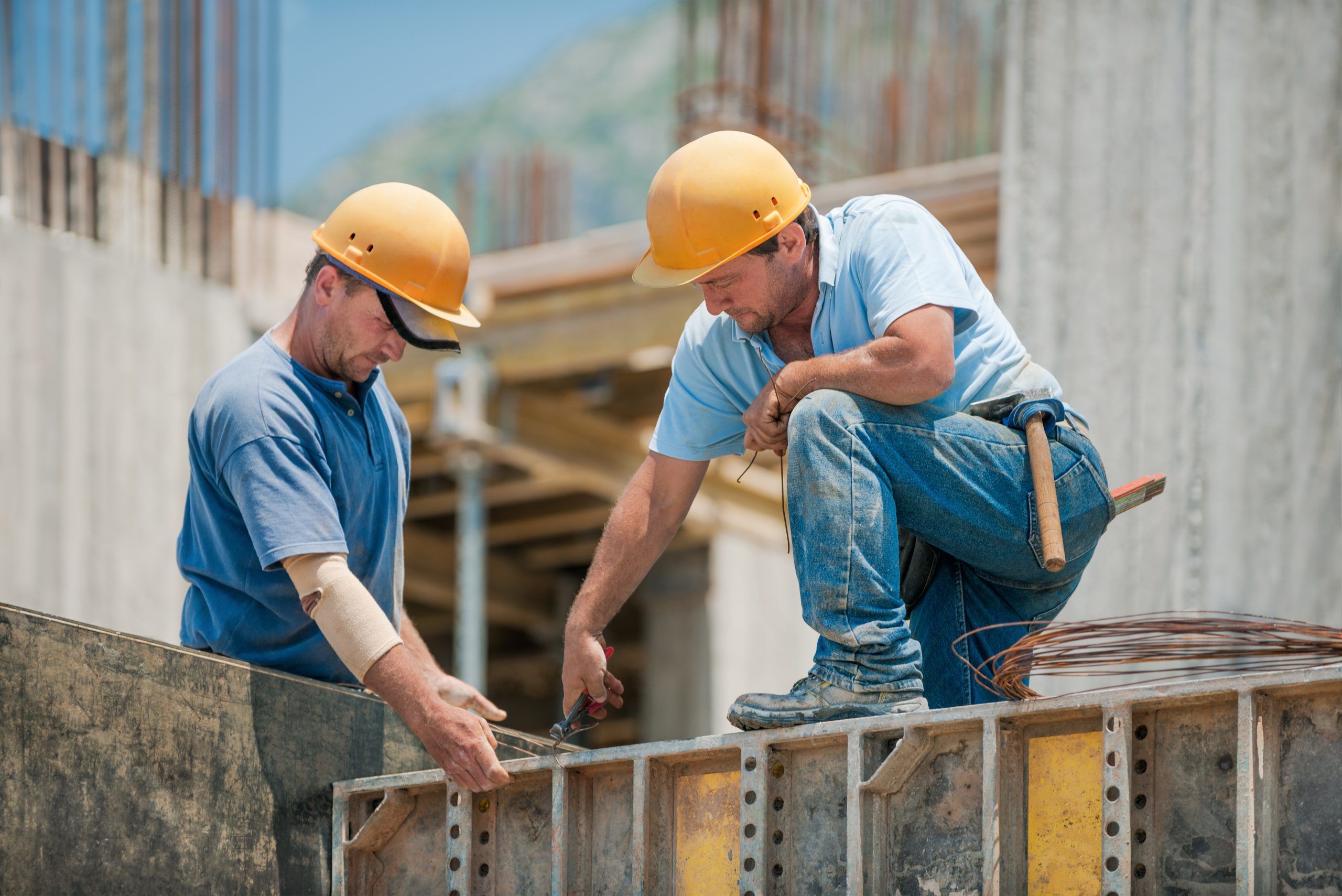 Two authentic construction workers collaborating in the installation of concrete formwork frames